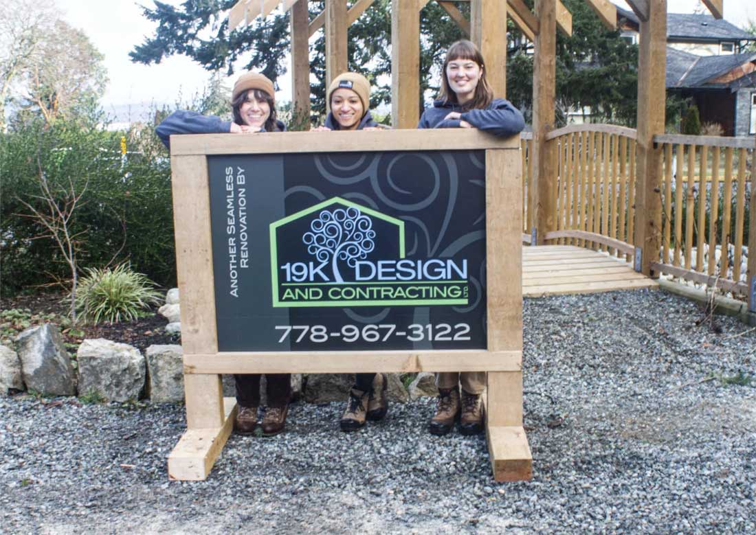 Three people behind a company sign.